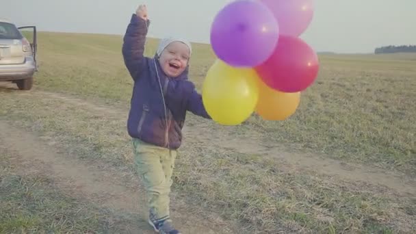 Šťastný chlapeček, zábavný pobítý kolem balónků. Venkovní rekreace. Večerní slunce. - Záběry, video