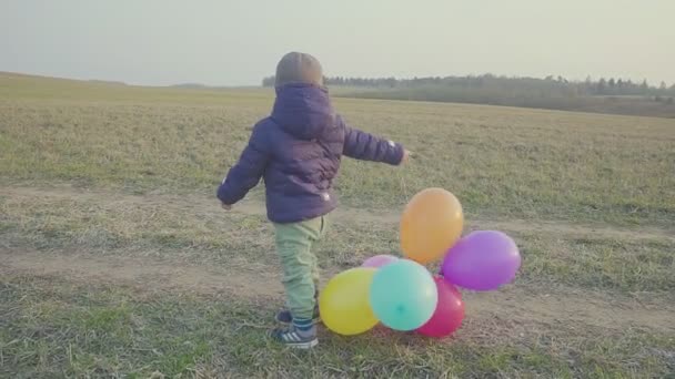 Onnellinen poikavauva, hauska juoksennella ilmapallojen kanssa. Ulkona virkistäytyminen. Iltaauringonlaskussa
. - Materiaali, video