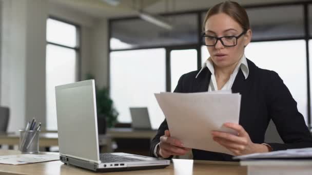 Young woman secretly reading magazine in office, lazy employee avoiding work - Кадри, відео