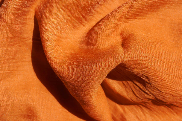 Textur aus orangefarbenem Stoff. Textur t ist hellbraunes Textilmaterial. Nahaufnahme mit rotem Schal. dunkelgelber Pfälzer. - Foto, Bild