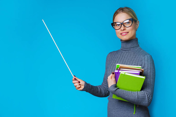 Photo of woman teacher with pointer and books in their hands - Foto, imagen