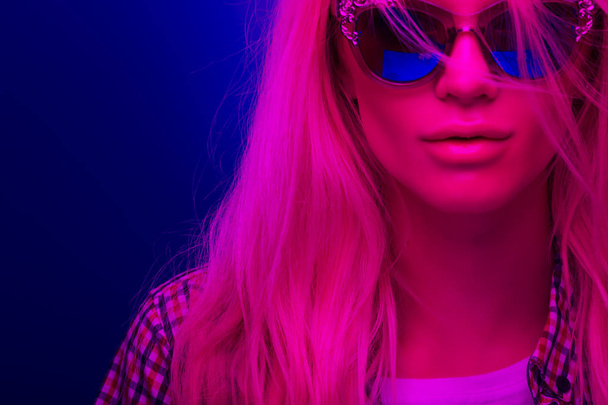 Neon closeup portrait of a young woman in sunglasses - 写真・画像