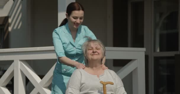 Gyógytornász masszírozó Senior nő Kórház rehabilitációs központ szabadban, a Sunny Day shot a piros kamera - Felvétel, videó