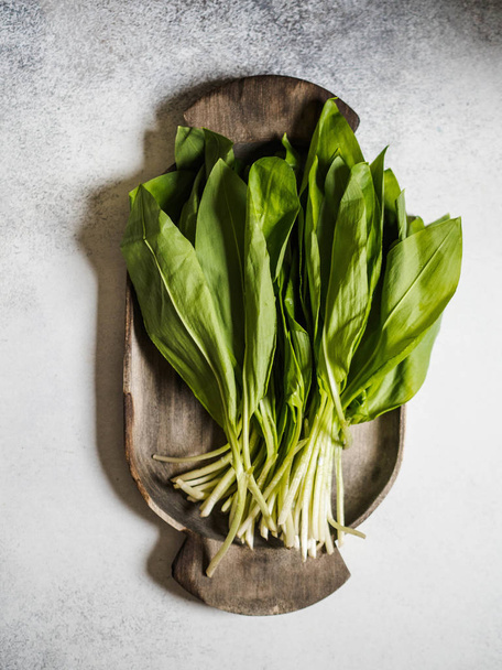 Bunch Fresh harvest of spring ramson or wild leek herb leaves bunch on rustic wooden tray on grey background - Photo, Image