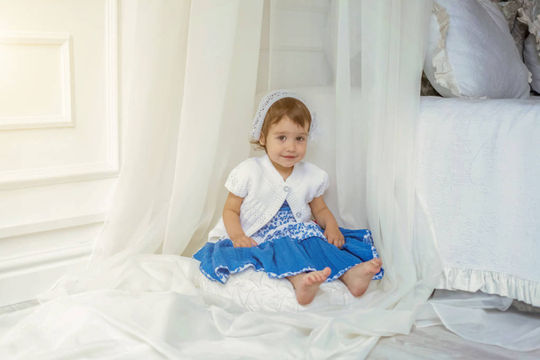 Cute little girl playing in light white bedroom - Foto, imagen
