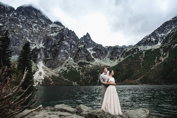 Young wedding couple posing on the shore of the lake Morskie Oko. Poland, Tatra - Foto, afbeelding