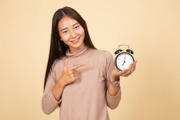 Young Asian woman point to a clock. - Zdjęcie, obraz