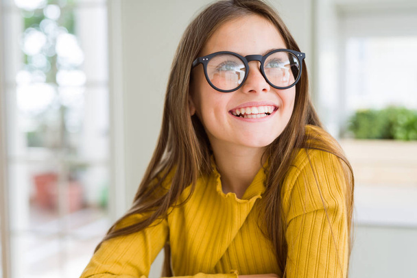 Beautiful young girl kid wearing glasses smiling looking side and staring away thinking. - Foto, Imagen