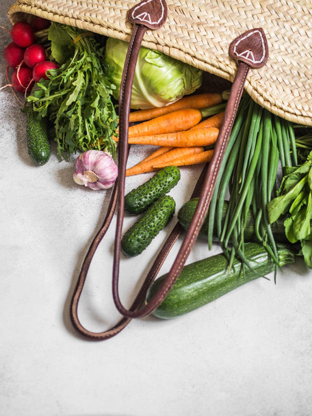 Ψάθινη σακούλα γεμάτη φρέσκα λαχανικά της άνοιξης. Υγιεινή χορτοφαγική χορτοφαγική τροφή από την τοπική αγορά από αγροκτήματα - Φωτογραφία, εικόνα