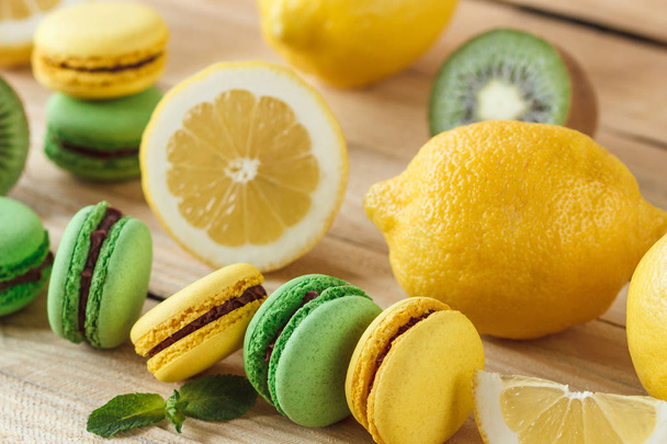 Green and yellow french macarons with kiwi, lemon and mint decorations - Foto, immagini