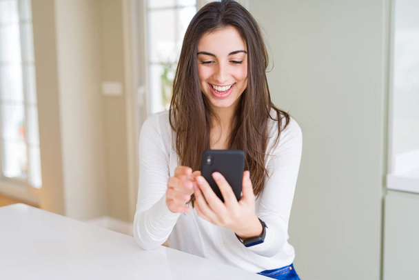 Fiatal nő használ smartphone, mosolygó boldog textil és gépelés - Fotó, kép