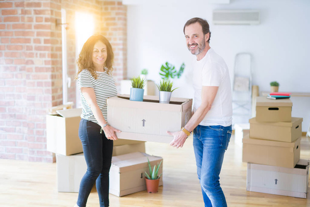 Moyen âge couple âgé déménageant dans une nouvelle maison, tenant la boxe en carton souriant heureux en amour avec apartmant
 - Photo, image