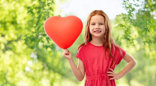 smiling red haired girl with heart shaped balloon - Foto, Bild