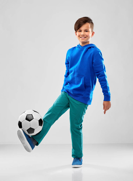 smiling boy in blue hoodie playing soccer ball - 写真・画像