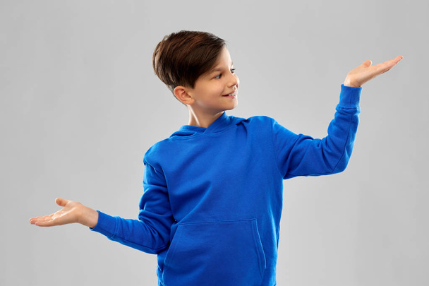 boy in blue holding something on empty hands - Фото, изображение