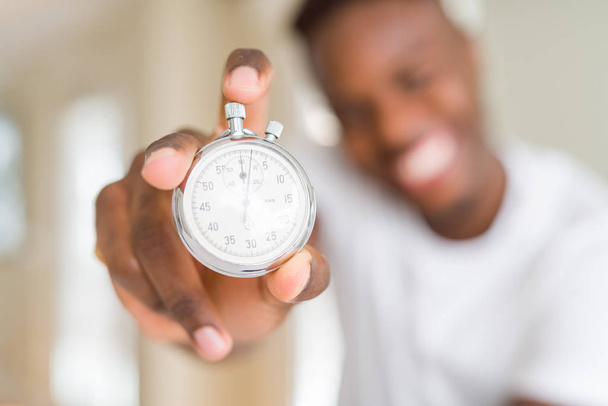 Joven africano sosteniendo cronómetro retro plateado contando el tiempo
 - Foto, Imagen