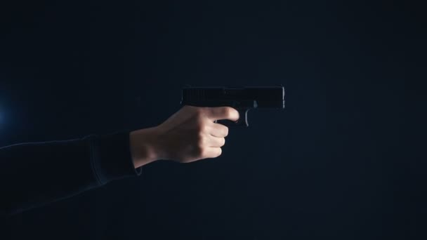 Close-up pistool in de hand op een zwarte achtergrond. - Video