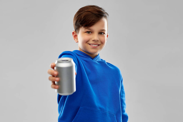 smiling boy in blue hoodie holding can drink - Foto, Bild