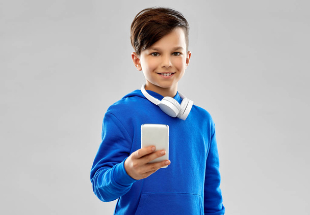 smiling boy in blue hoodie using smartphone - Fotoğraf, Görsel
