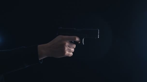 Close-up pistool in de hand op een zwarte achtergrond. - Video