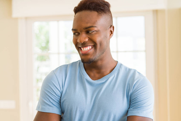 schöner afrikanischer junger Mann lächelt fröhlich mit einem breiten Lächeln auf  - Foto, Bild