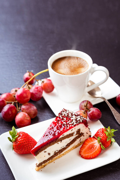 Dessert und Kaffee. eine Tasse heißen Kaffee mit Crema, Kuchen und Obst. Trauben, Erdbeeren und Obstkuchen. Stillleben auf dunklem Hintergrund - Foto, Bild