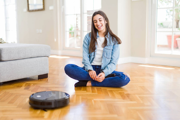 Young woman using automatic vacuum cleaner to clean the floor, c - Foto, imagen