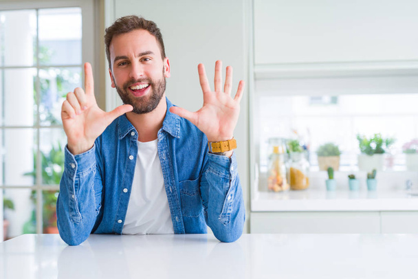 Hombre guapo en casa mostrando y señalando hacia arriba con los dedos número siete mientras sonríe confiado y feliz
. - Foto, imagen