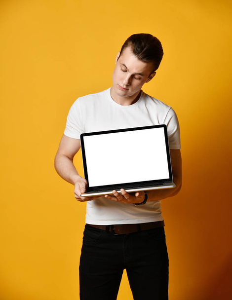 A handsome young man holding and showing the screen of a laptop - Zdjęcie, obraz