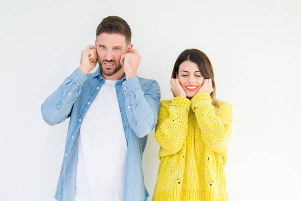 Young beautiful couple togheter over isolated background covering ears with fingers with annoyed expression for the noise of loud music. Deaf concept. - Photo, Image