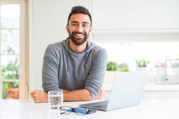 Jóképű hispán ember dolgozik a számítógép laptop egy boldog és hűvös mosoly az arcon. Szerencsés ember. - Fotó, kép