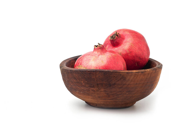ripe, juicy pomegranate in wooden bowl on white background - Фото, зображення