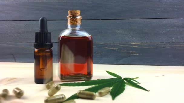 Bottiglie di vetro con olio di cannabis CBD e capsule di CBD versate al rallentatore sul tavolo
 - Filmati, video