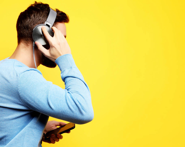 young man wearing headphones and holding mobile phone - Foto, Imagen