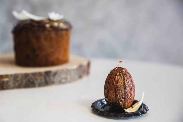 Handmade chocolate with gold easter egg with easter cake on background. - Foto, afbeelding