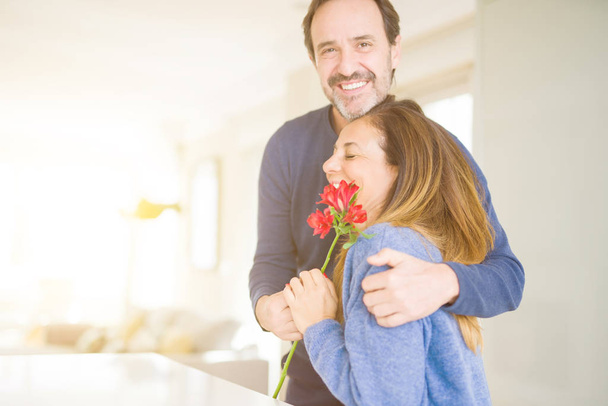 Romântico casal meia idade segurando flores no amor em casa
 - Foto, Imagem