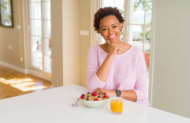 Mladá africko-americká žena, která ráno snídala doma, se dívala na fotoaparát s úsměvem s zkřížené paže a rukou zdviženou bradu. Pozitivní myšlení. - Fotografie, Obrázek