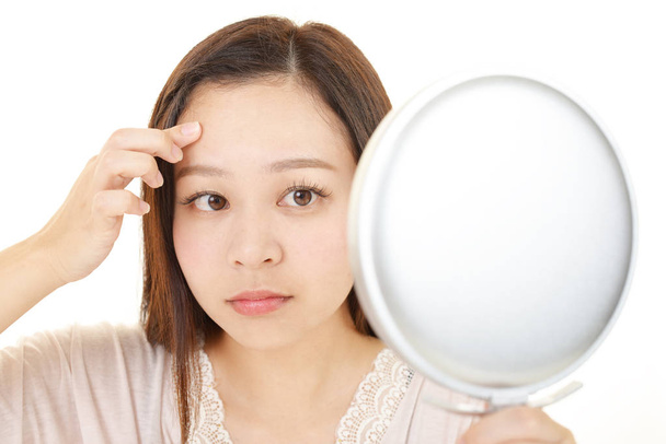 Asijské žena pohled na ji tvář v zrcadle - Fotografie, Obrázek