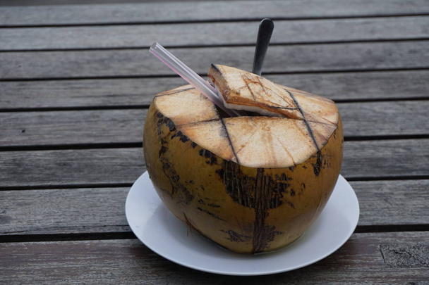 木製のテーブルの上のココナッツカクテルは、この夏休みに飲む準備ができています - 写真・画像