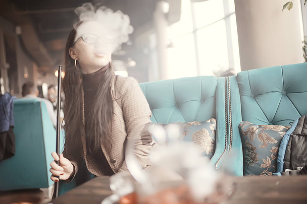 adult girl smokes a hookah in a cafe / modern interior, smoking, smoke, night club, day. - Photo, image