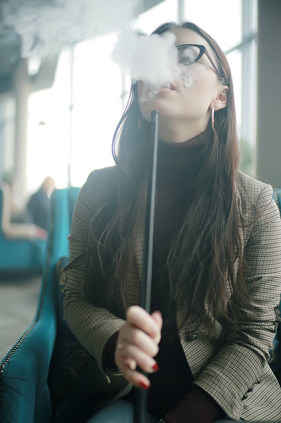 adult girl smokes a hookah in a cafe / modern interior, smoking, smoke, night club, day. - Zdjęcie, obraz