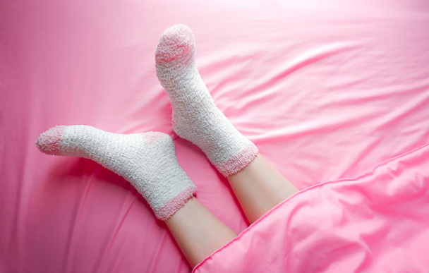 Women wearing socks in winter morning and blankets background. Warm and cozy on bedding sheet. - Φωτογραφία, εικόνα