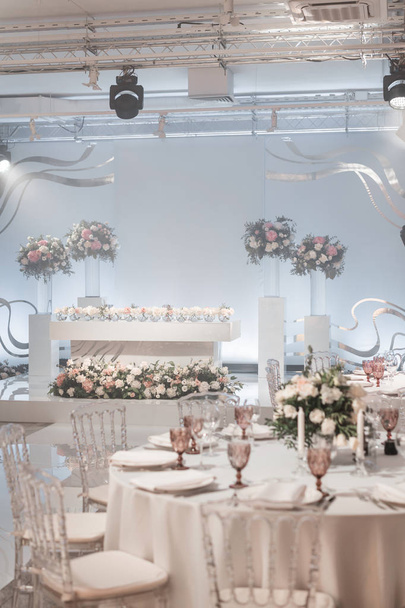 The table of the newlyweds. Small flower arrangements in ball glass vases. Interior of restaurant for wedding dinner, ready for guests. Catering concept. - Photo, Image