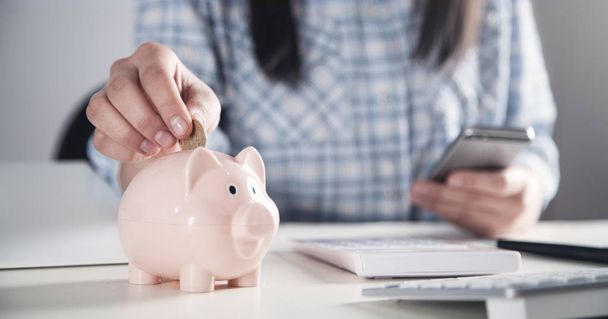 Business girl putting coin in a piggy bank. Saving money - Photo, Image