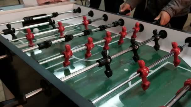 People Play Table Soccer. Red and black pieces of foosball players spin and hit the ball. Hands twist levers to hit the ball. Table soccer player kicking the football at goal - Footage, Video