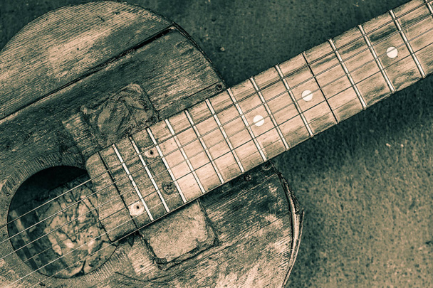 παλιά κιθάρα σε τσιμεντένιο τοίχο φόντο με θολή μπροστά και ΒΑ - Φωτογραφία, εικόνα