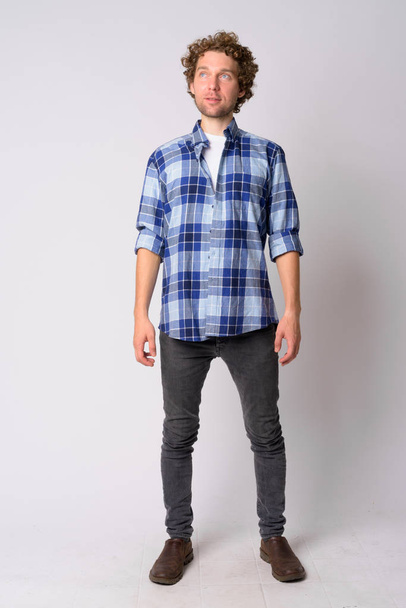 Full body shot of handsome hipster man with curly hair thinking - Foto, afbeelding