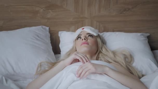 Jeune femme dormir sur un lit confortable dans un masque pour dormir. Les yeux bandés. Bonjour dans la chambre d'hôtel. Oreiller blanc et couverture
 - Séquence, vidéo