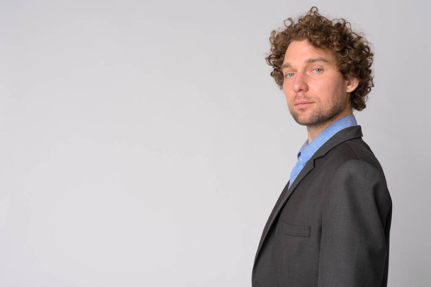 Profile view of handsome businessman with curly hair looking at camera - Fotografie, Obrázek