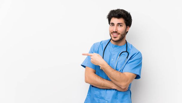Surgeon doctor man over isolated white wall pointing finger to the side - Foto, Imagem